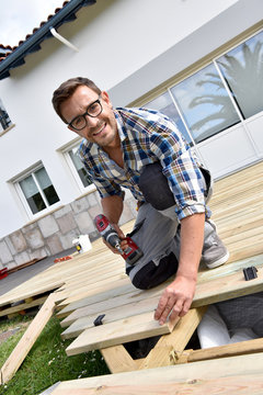 Smiling carpenter buidling wooden deck