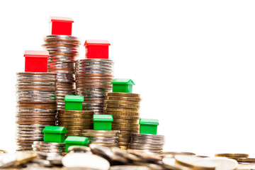 Stacks of coins, green and red home. Mortgage concept by money house from coins
