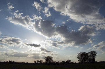 Naklejka na ściany i meble Sun behind clouds over meadows