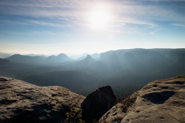 Fototapeta premium Dreamy misty morning in forest landscape. Majestic peaks cut lighting mist. Deep valley
