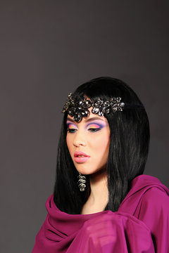 Portrait of a beautiful young woman in a purple cloth, dark stud