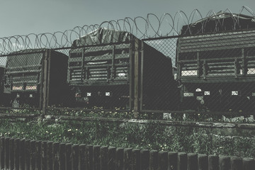 military warehouse, military vehicles, behind the fence, an old dark background