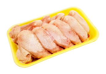 Frozen chicken wings in the yellow tray on the light background