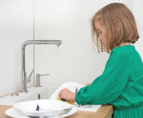 Little girl washing dishes in the kitchen.