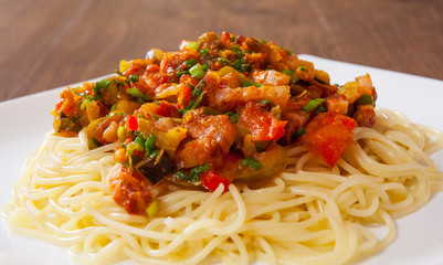 Spaghetti pasta with vegetables mix and bacon on white plate