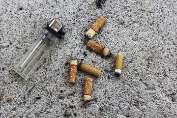 Lighter and cigarette butts on the ground.