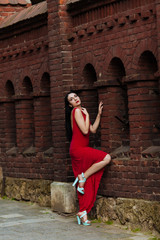 young sensual woman with long curly hair on dark old brick wall background