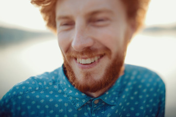 Outdoor portrait of young handsome smiling ginger man