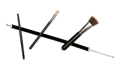 black velvet ribbon and three makeup brushes on white background