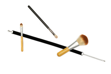 black velvet ribbon and three makeup brushes on white background