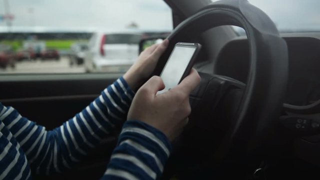 Woman using mobile smart phone while driving car, dangerous behavior in traffic