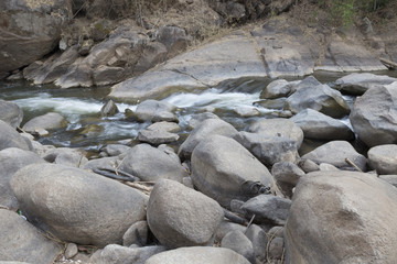 Naklejka na ściany i meble water stream through stone in creek