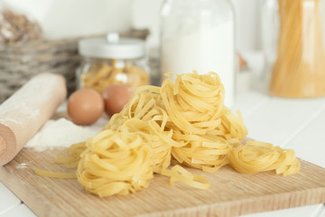 Uncooked dried tagliatelle over cutting board with flour and eggs