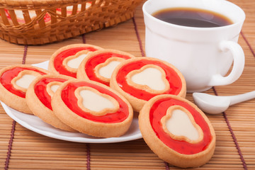 cookies with jelly and cup of coffee on bamboo napkin