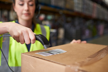 Woman using barcode reader on a box in a warehouse, detail - obrazy, fototapety, plakaty
