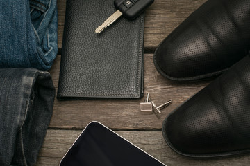 Male set for day from wallet, jeans, smartphone and car key on wooden board.