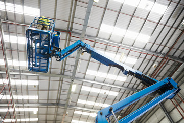 Low angle view of a cherry picker being used in a warehouse