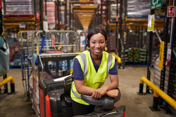 Woman leaning on a tow tractor in a distribution warehouse