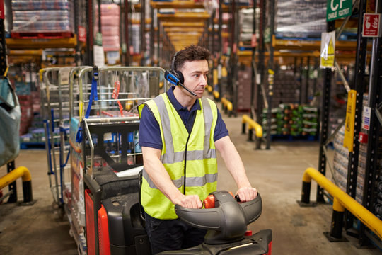 Man driving a tow tractor through a distribution warehouse