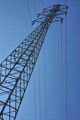 Very high electricity pylon during the sunny day with bright sun and blue sky 