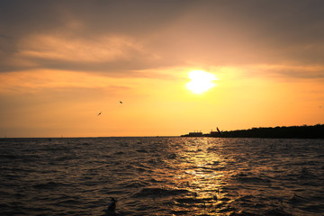 Sunset at sea, with oil industry in the background.