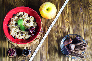 Healthy vs unhealthy food. Concept of making choice of food: fruit, oatmeal or candy, separated by a measuring tape. Time for slimming.