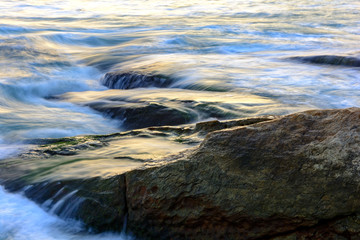 Sea water moving between the rocks during sunset