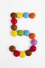 Il numero 5 formato da coloratissimi confetti di cioccolata.