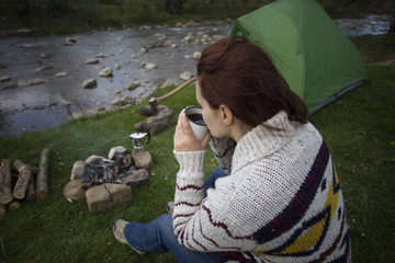 Girl sitting near a campfire.