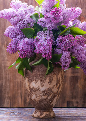 Lilac flowers. Bouquet of lilac flowers in a ceramic vase on a wooden