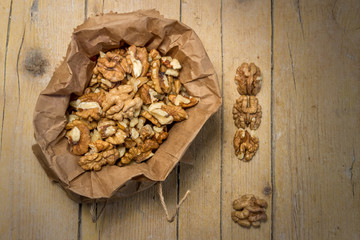 Грецкий орех в крафтовом пакете на деревянном фоне. Здоровое питание.