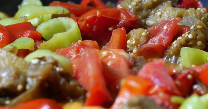 Close-up shot of vegetables stewing in the pan. Appetizing vegetarian dish with egg-plants, peppers and tomatoes