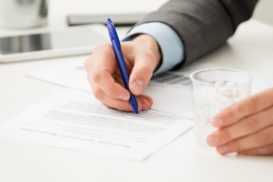Businessman hand filling in business document  