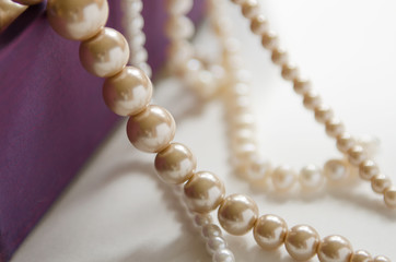  few beads of pearls hanging on a purple gift box