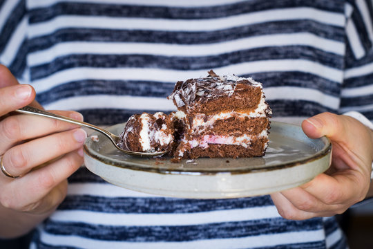 Women's hands holding plate with a piece of Black Forest cake. Selective focus.
