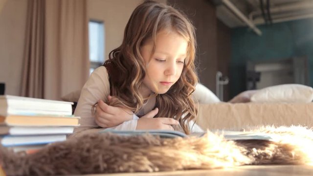 девочка читает книгу лежа на полу