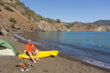 A man traveling by canoe along the coast in the summer.