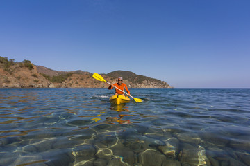 A man traveling by canoe along the coast in the summer.