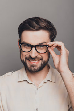 Portrait of attractive happy young man in glasses on gray backgr