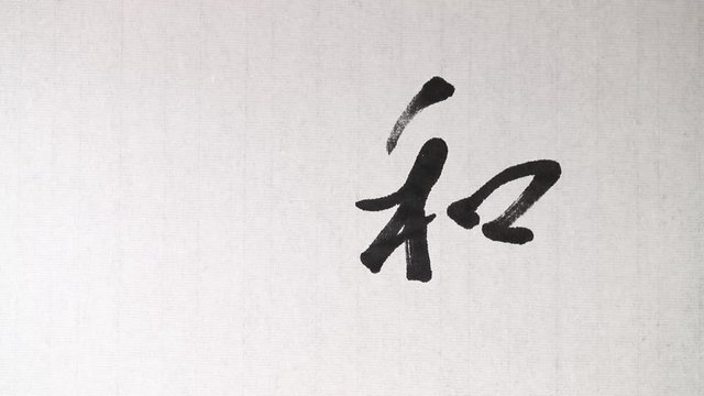 Handwriting of Chinese characters which mean "PEACE", with ink and a brush, on rice paper.