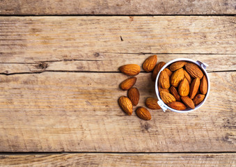 Roasted grains of peanuts in a wooden bucket isolated on white background, view from above