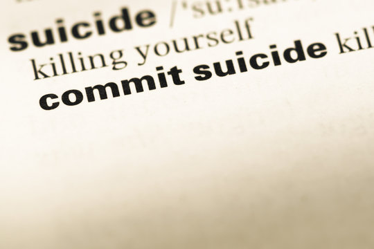 Close up of old English dictionary page with word commit suicide