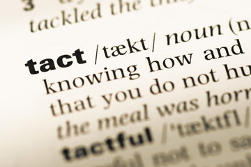 Close up of old English dictionary page with word tact