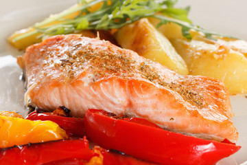 Grilled salmon fillet with vegetables, spices and arugula on a plate