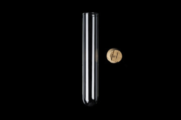 Glass transparent test tube with cork on side on black background