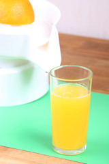 orange on squeezer, juicer and glass of orange juice on the table