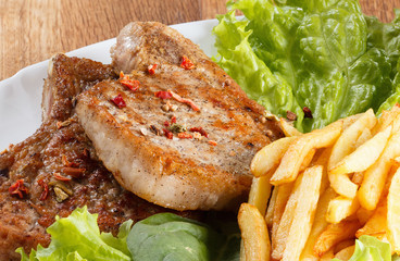 Juicy roasted pork steak with french fries and spices