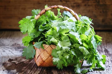 Zelfklevend Fotobehang Fresh cilantro in a wicker basket, vintage wooden background, se © 5ph