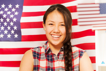 Smiling teenage girl with American flag behind her