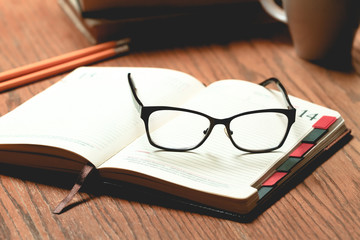 Glasses, book and cup of tea on a wooden table